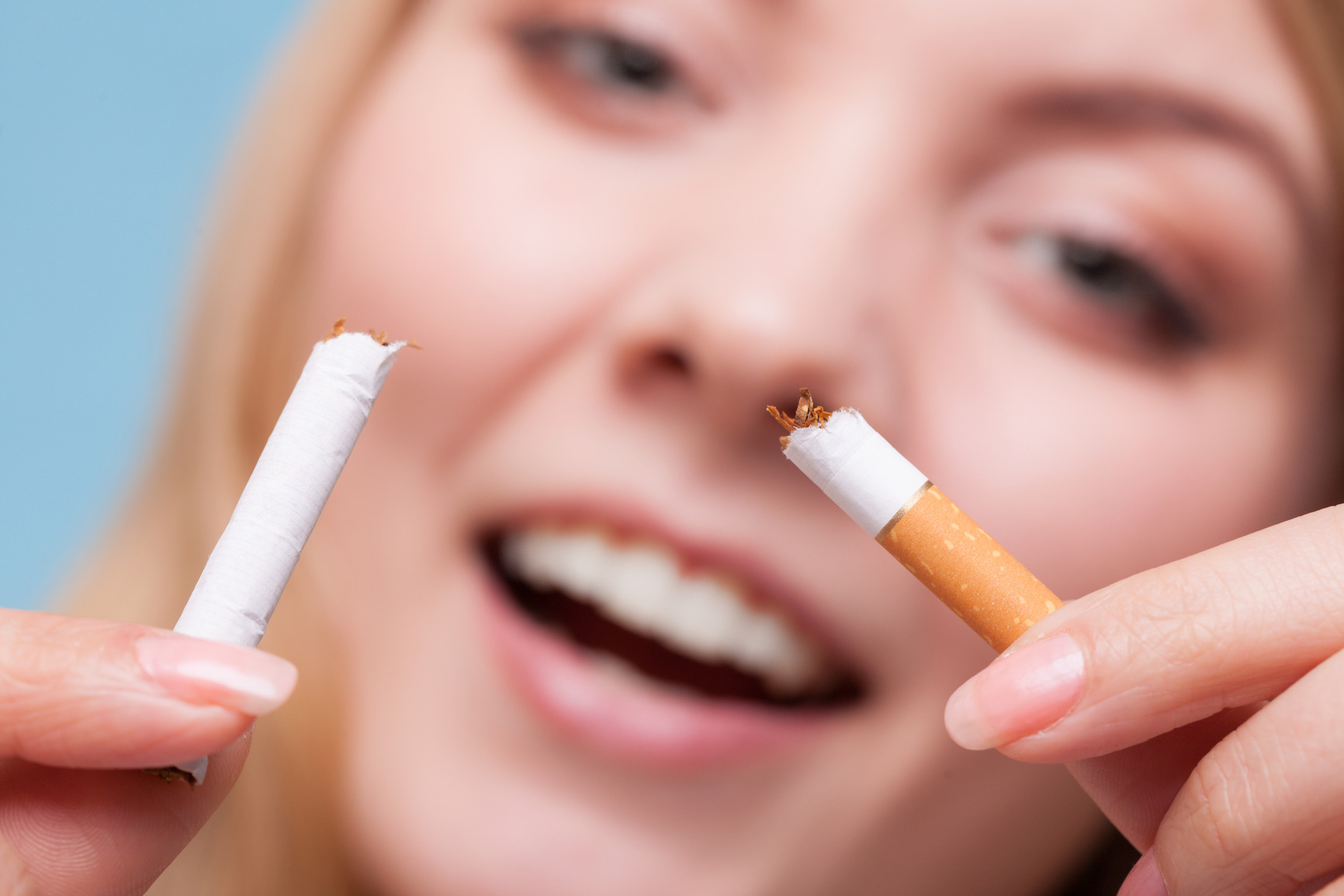 Addiction. Closeup of young woman determined girl breaking the cigarette. Quit smoking. Studio shot.